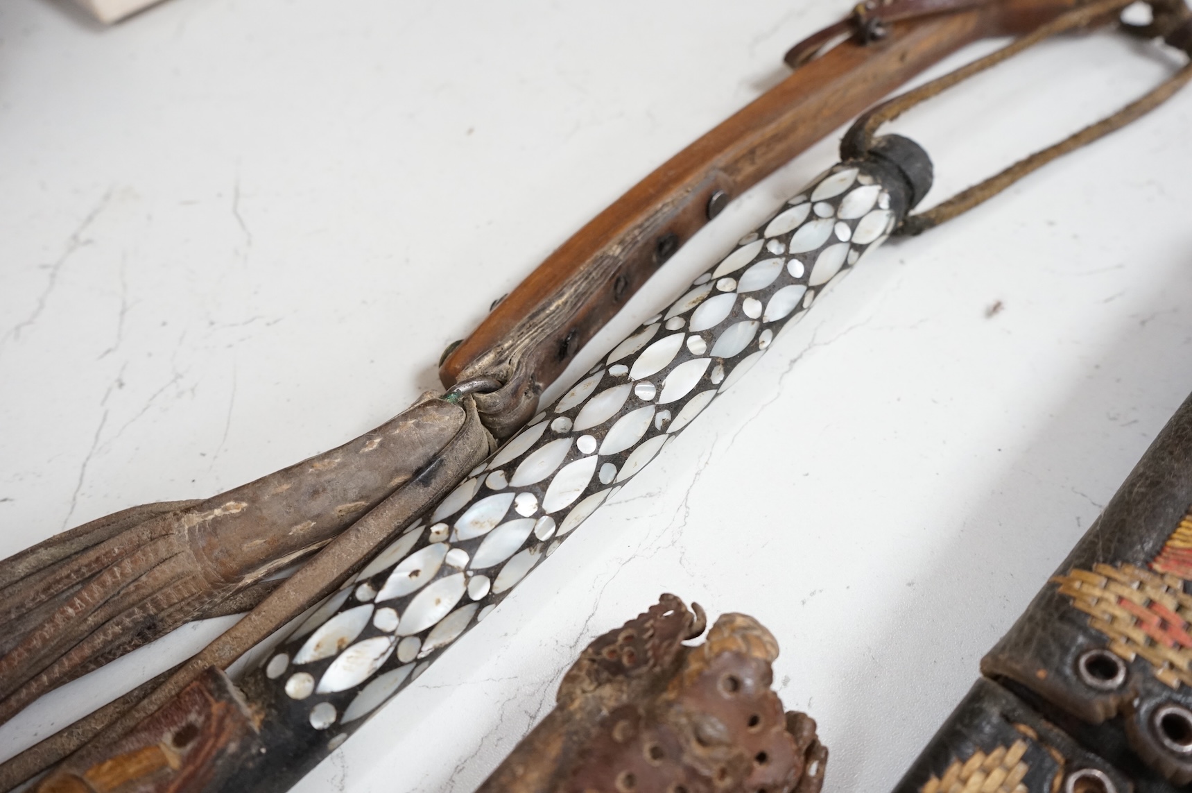 An Argentinian braided leather belt and whips, one with mother of pearl inlay